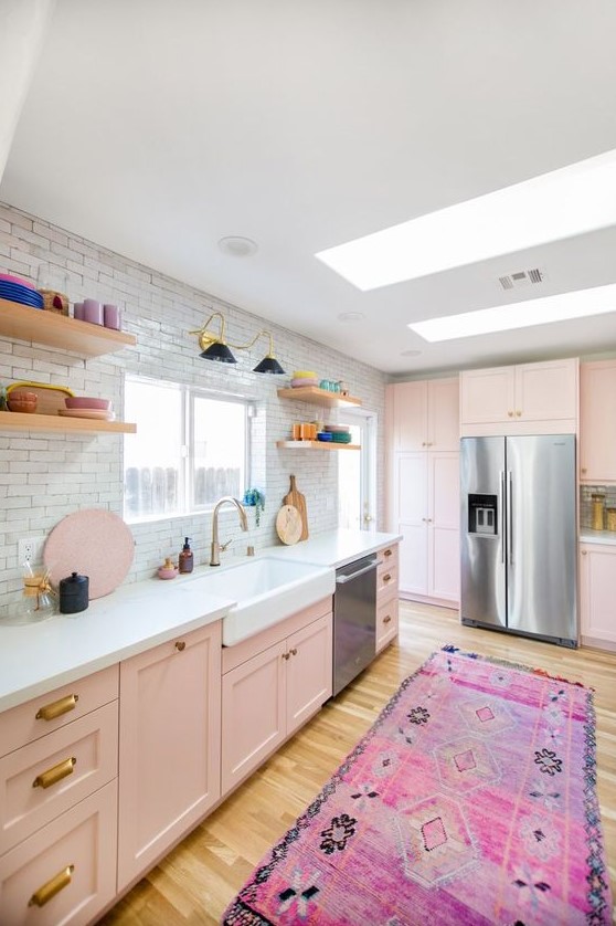 an eclectic kitchen with blush cabinets, a white tile backsplash, open shelves and colorful tableware