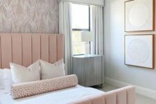 an elegant and laconic feminine bedroom with a wallpaper wall, a pink bed, a catchy chandelier and abstract artworks