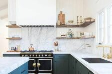 an elegant dark green kitchen with shaker cabinets, a large white hood, a white quartz backsplash and countertops