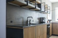 an industrial kitchen with black cabinets with fluted doors, open shelves instead of upper cabinets and black fixtures and countertops
