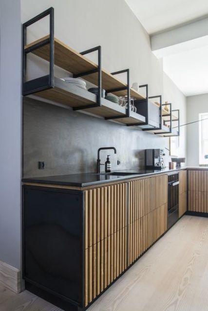 an industrial kitchen with black cabinets with fluted doors, open shelves instead of upper cabinets and black fixtures and countertops
