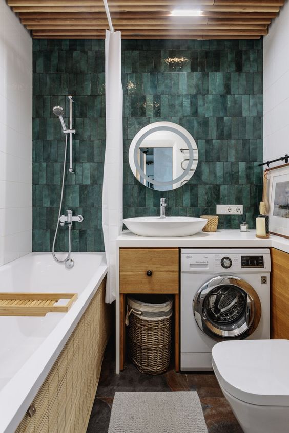 a bright and cool bathroom with a green skinny tile wall, a tub, a timber vanity with a built-in washine machine