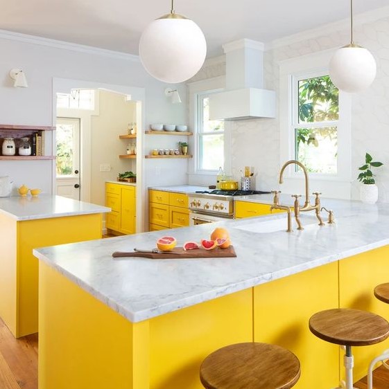 a bright kitchen done with yellow cabinets, white stone countertops and all white everything for a chic and bold look