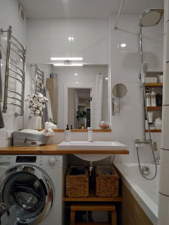 a modern white bathroom with a bathtub, an open timber vanity with a washing machine, a mirror and built-in shelves