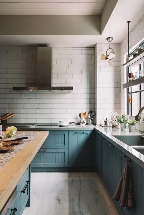 a catchy teal kitchen with vintage cabinets, a white tile backsplash, stone and butcherblock coutnertops and stainless steel fixtures