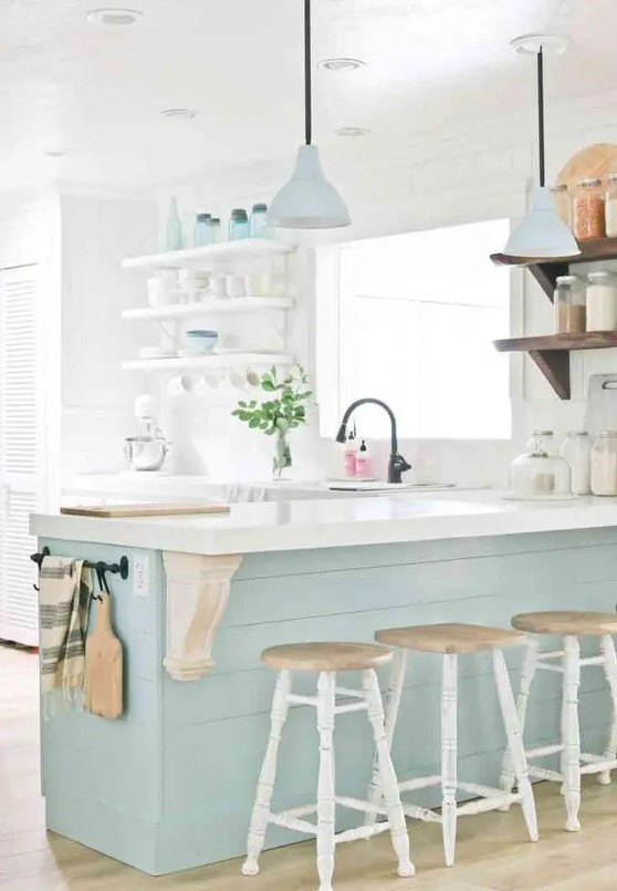 a dreamy coastal kitchen with white open shelving, a mint blue kitchen island, matching pendant lamps and tableware, vintage stools and black fixtures
