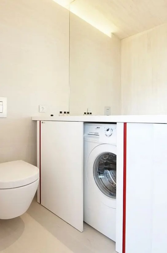 a neutral bathroom with a mirror, a large vanity with sliding doors that hides a washing machine and a toilet