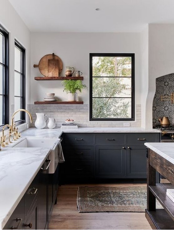 a chic dark grey farmhouse kitchen with white quartz countertops and a white marble tile backsplash, stained floating shelves and mixed metals