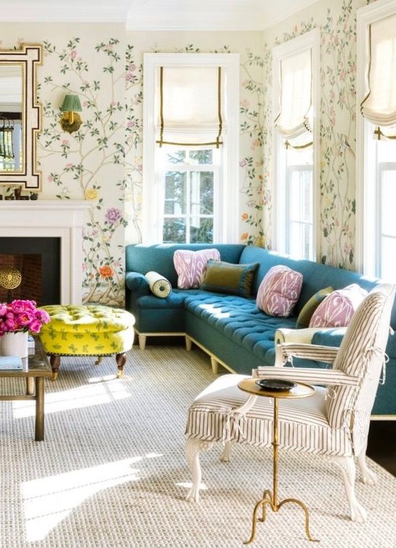 a pretty and chic living room with bright floral wallpaper, a navy sectional, a striped chair, a non-working fireplace, a bold neon yellow ottoman