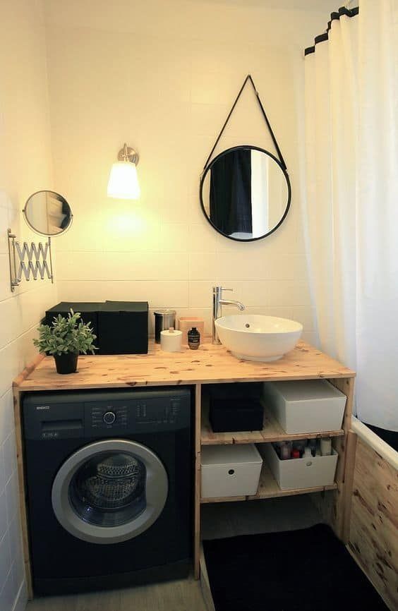 a small black and white bathroom with a black washing machine built in the vanity, a small mirror and a shower space