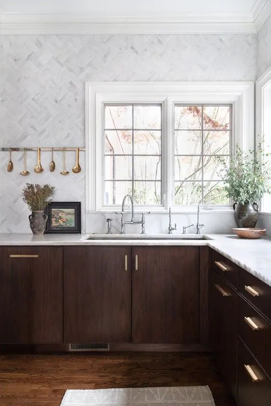 a jaw-dropping walnut kitchen with white stone countertops and white marble tiles plus touches of gold