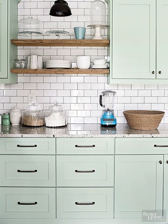 a mint green kitchen with shaker style cabinets, open stained shelves, a white subway tile backsplash and neutral granite countertops