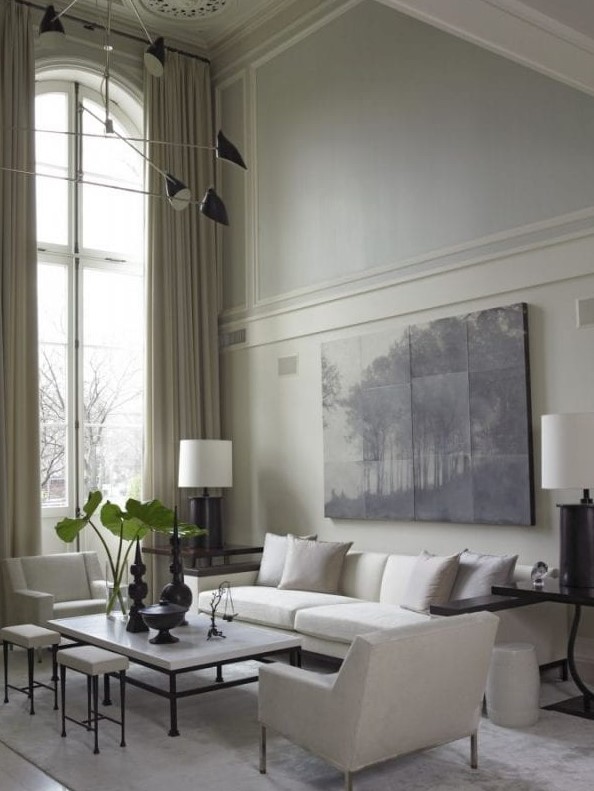 a neutral living room with white seating furniture and a coffee table, an artwork and some trim on the walls
