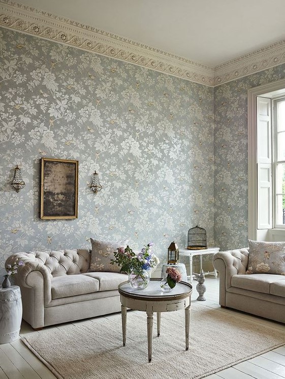 a sophisticated vintage living room with blue floral wallpaper, neutral seating furniture, side and coffee tables and lanterns