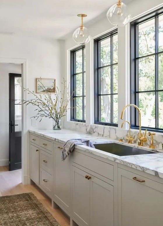 a refined greige kitchen with a white marble countertop and gold fixtures and a faucet is a stylish idea