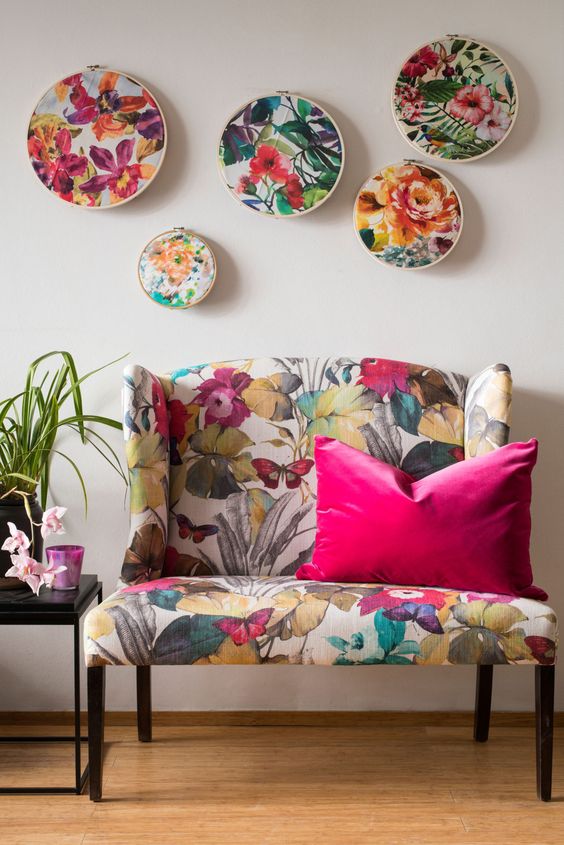 a bold floral loveseat, a gallery wlal with floral embroidery are cool and bright additions to a living room