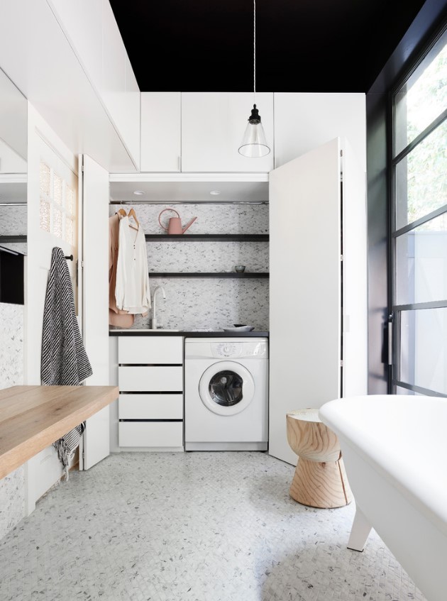 a beautiful neutral bathroom clad with white terrazzo, with a free-standing tub, a floating vanity and a hidden washing matchine in a large storage unit