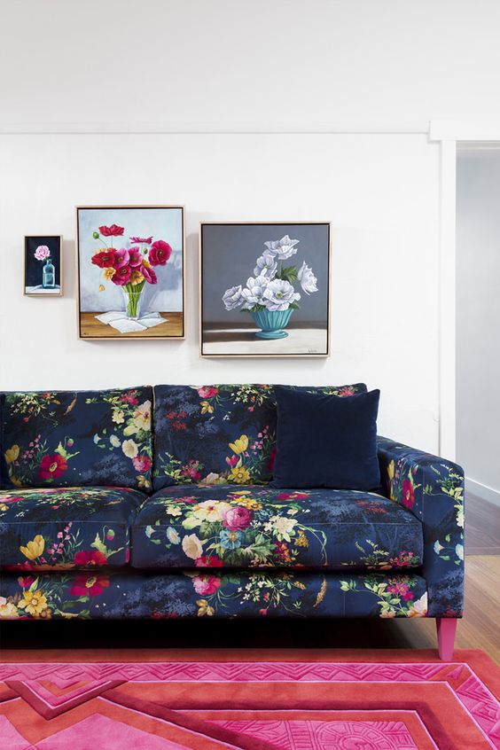 a bold living room with a navy floral sofa, a hot pink rug and a mini gallery wall with floral artwork