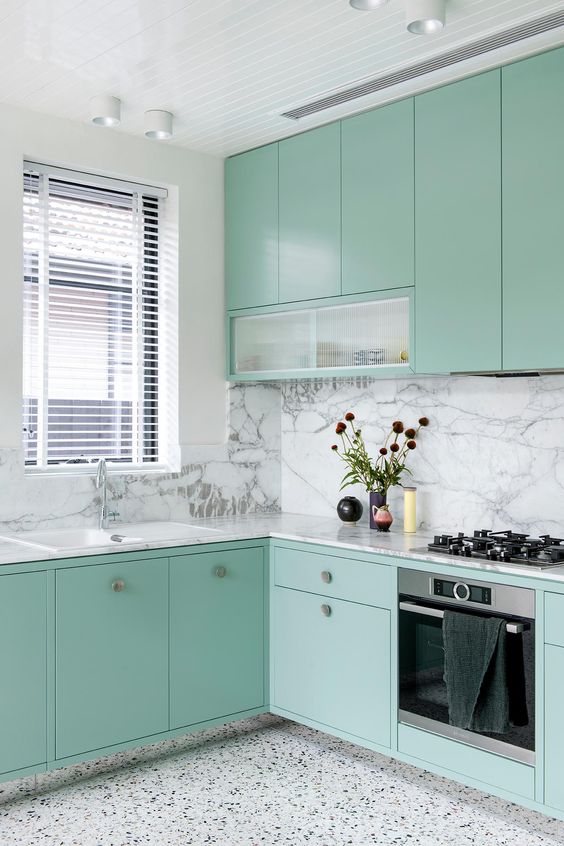 a modern kitchen in mint green, with a white marble backsplash and a white terrazzo floor plus touches of black is pure chic