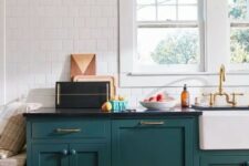 16 a stylish mid-century modern teal kitchen with black countertops, a white tile wall and touches of gold here and there