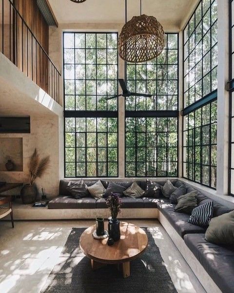 a welcoming contemporary living room with a corner sofa and pillows, glazed walls, a stained oval coffee table, a woven pendant lamp