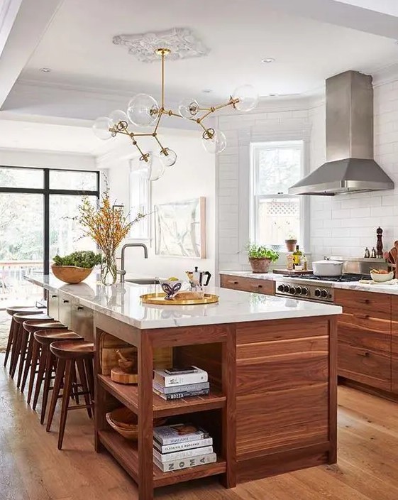 a welcoming mid-century modern walnut kitchen with stylish cabinets and a large kitchen island, white stone countertops and a catchy chandelier