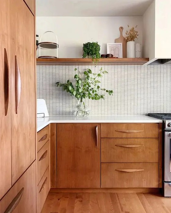 a beautiful mid-century modern kitchen with stained cabinets, a white tile backsplash and white countertops, greenery for a fresh look