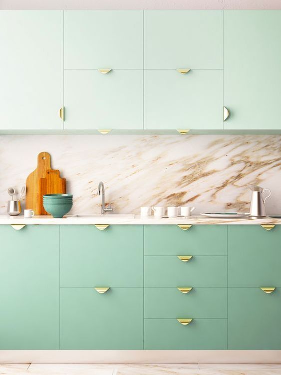 a two-tone kitchen with mint green and brighter green cabinets, a marble backsplash and countertops, gold pulls is amazing