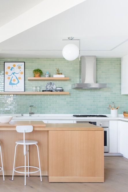 a welcoming modern kitchen with sleek white cabinets, a glossy mint green tile backsplash, a stained kitchen island and open shelves