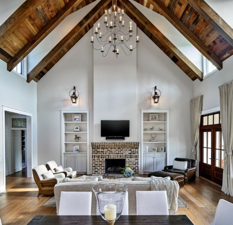 an attic living room with skylights and wooden touches that accent the ceiling, a fireplace, bookcases, neutral seating furniture