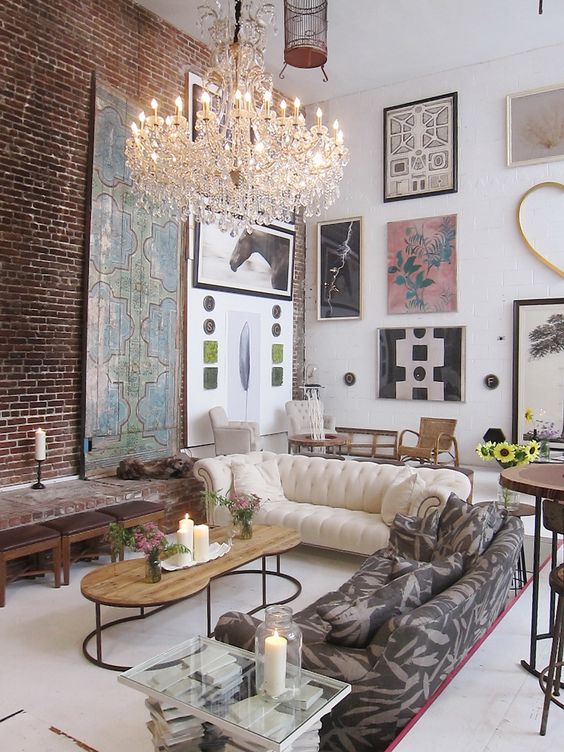 a beautiful living room with a gallery wall, a white upholstered sofa, a printed one, a coffee table, brown stools and a gorgeous chandelier