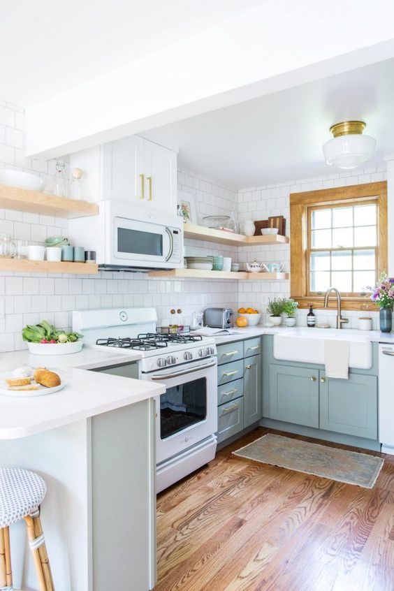 a chic mint blue kitchen with shaker cabinets, white countertops, a white square tile backsplash and open shelves is a very welcoming space