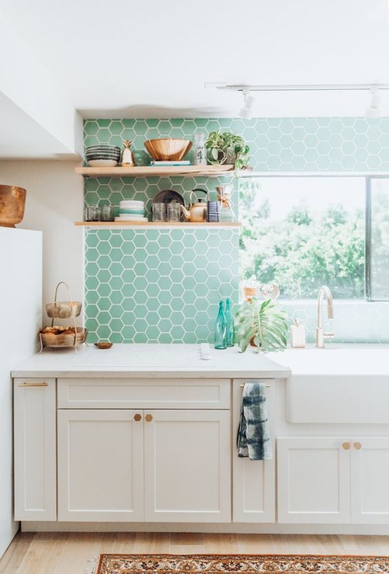 a white farmhouse kitchen with mint green hexagon tiles, open shelves, white countertops and potted plants is a chic space