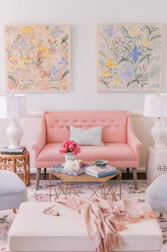 a beautiful and sweet pastel living room with a pastel pink sofa and pale blue chairs, pastel floral artworks and a rug plus chic side tables