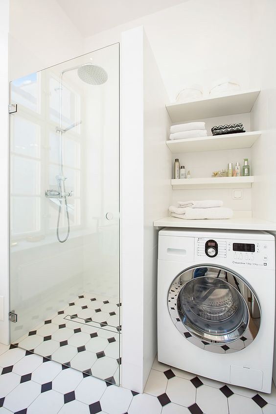 a black and white bathroom with a shower space, built-in shelves and a washing machine looks cohesive and harmonious