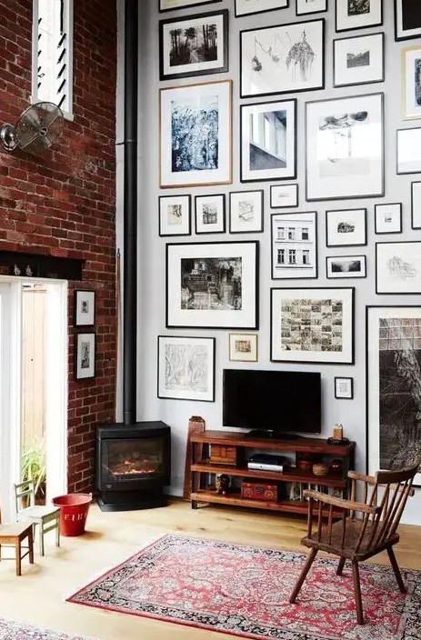 a cool gallery wall done with matching neutral and black frames of various sizes and with prints is a stylish idea