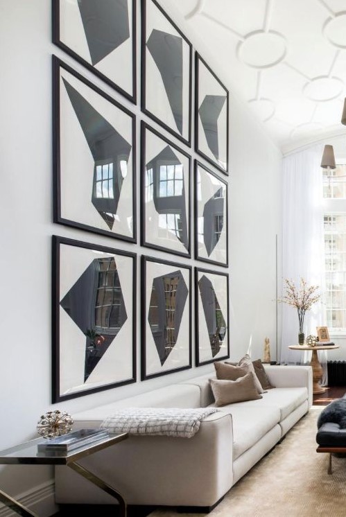 a dramatic and chic double-height living room with a bold gallery wall, a neutral sofa, neutral pillows and chic decor