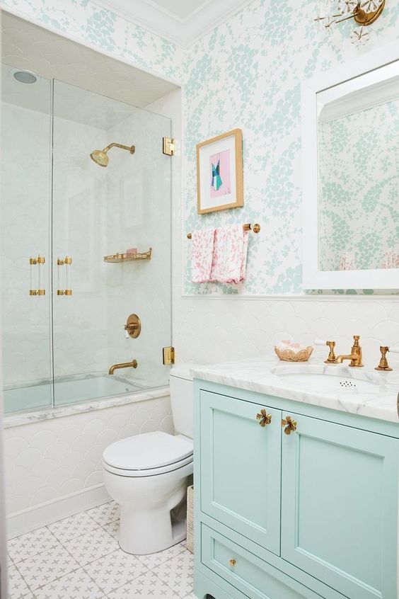 a chic bathroom with mint and white wallpaper, a mint vanity, a bath and shower space, brass and gold fixtures is very elegant