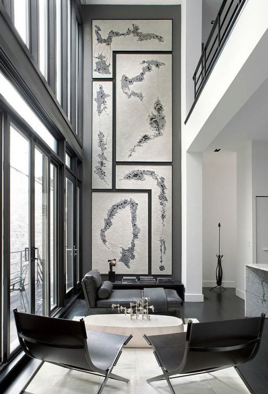 a dramatic living room with a glazed wall, a gallery wall, black and grey furniture, a neutral coffee table and a neutral rug