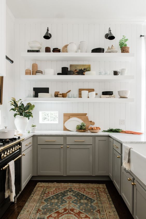 a grey farmhouse kitchen with shaker cabinets, a white beadboard backsplash, open shelves and white countertops plus black sconces