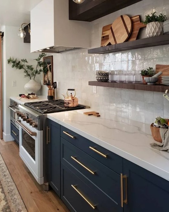 a navy shaker style kitchen with a white square tile backsplash and white quartz countertops plus brass touches and floating shelves