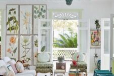 a pretty and eye-catchy living room with a white sofa and a woven sofa, turquoise chairs, a coffee table, printed chairs and a floral print wall