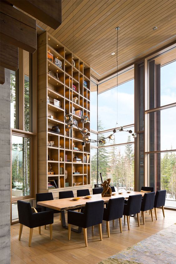 a beautiful formal dining room with glazed walls, a tall bookcase, a stained living edge table, black chairs and a bubble chandelier