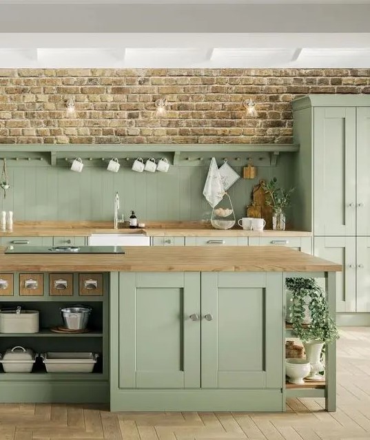 a rustic sage green kitchen with elegant vintage cabinetry, wooden countertops and neutral fixtures and handles