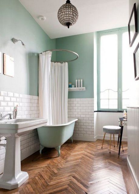 a mint blue bathroom with white subway tiles, a mint blue clawfoot tub, a free-standing sink and a chic pendant lamp