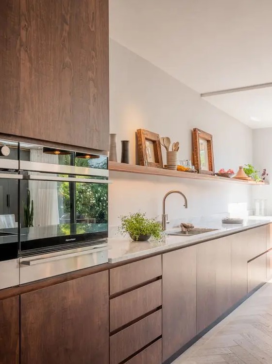 a sleek walnut kitchen with a Scandinavian design, a white tile backsplash and countertops plus touches of gold