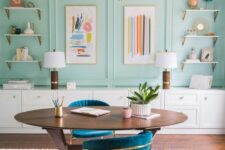 41 a mint blue home office with paneling, open shelves, bright artwork, a stained desk and navy chairs plus touches of gold