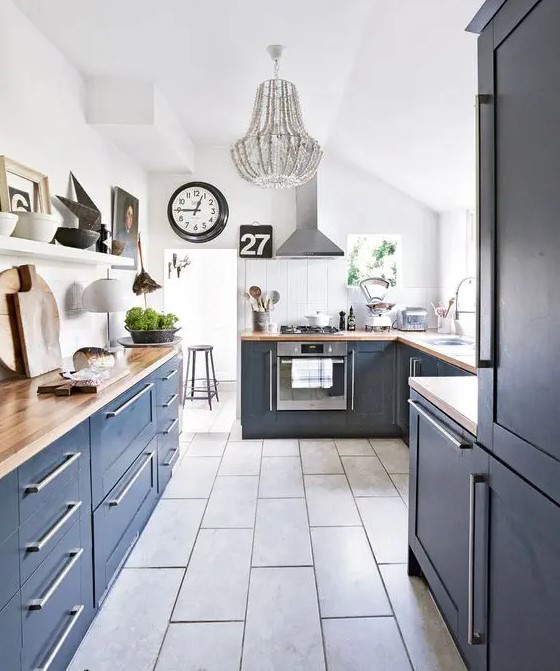 a stylish navy farmhouse kitchen with butcherblock countertops, a white ledge and a white beaded chandelier
