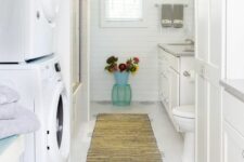 41 a white farmhouse bathroom clad with beadboard, with a large vanity, a bathtub and a stacked washing machine and a dryer