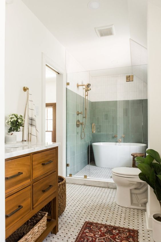 a mid-century modern bathroom with sage green tiles in the bathing zone, a printed tile floor, a stained vanity and a basket